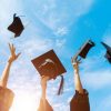 Four graduates throwing graduation hats in the air.